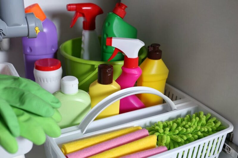 open under sink cabinet with different cleaning supplies in kitchen