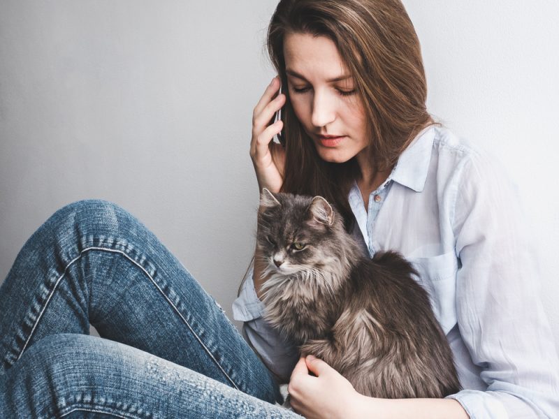 woman calling on her phone with her cat