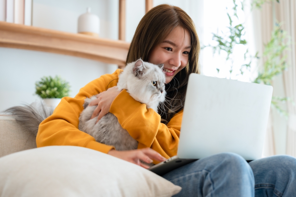 young cat owner with cat using her laptop